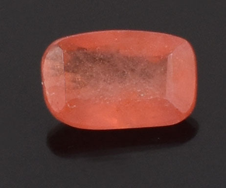 Faceted, translucent orange-red gemstone with a rectangular cushion cut.