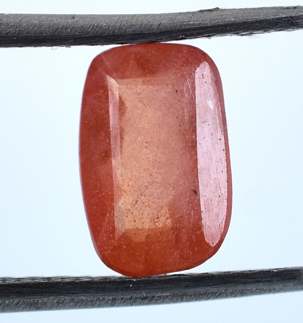 Cushion-cut orange-red gemstone, likely a padparadscha sapphire.