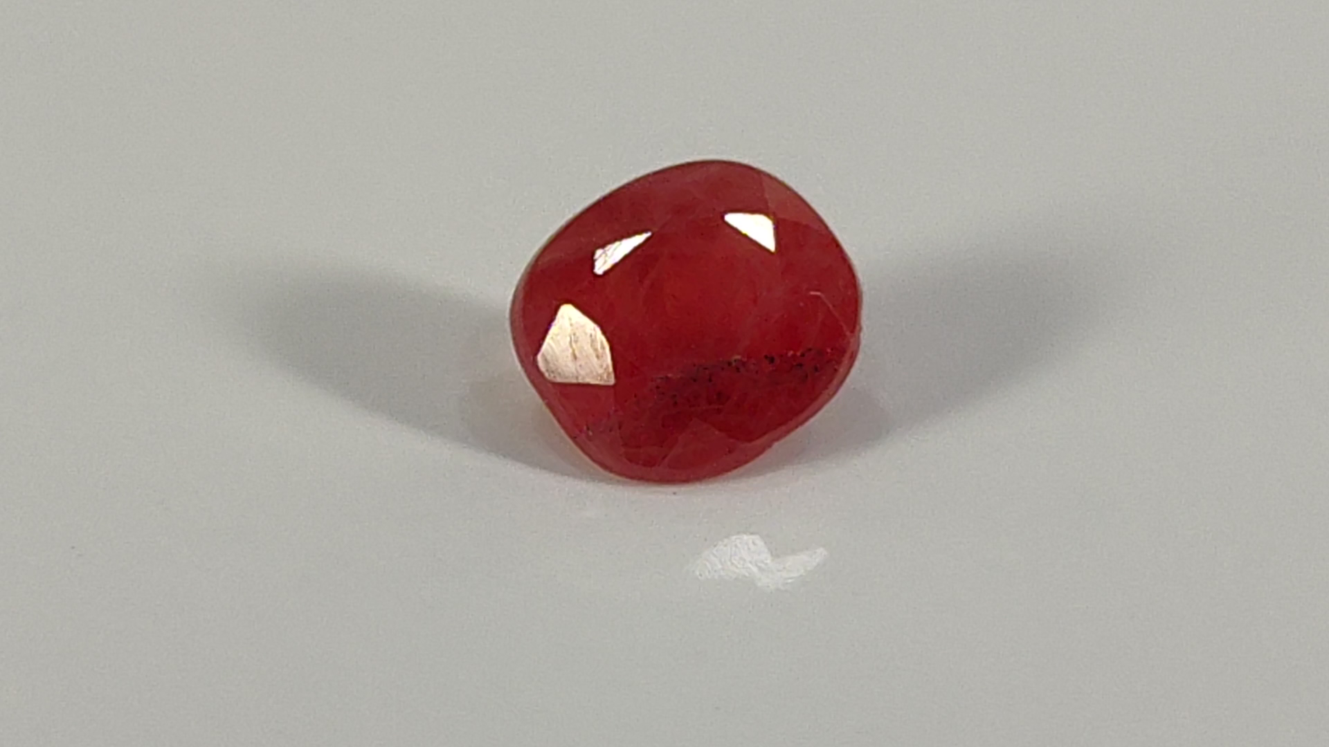 Red, translucent gemstone or crystal with faceted cuts.