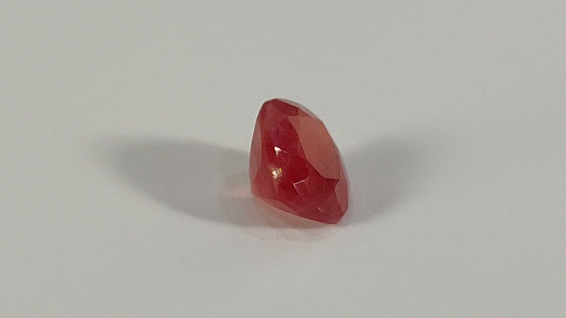 Red, translucent gemstone or crystal with faceted surfaces.