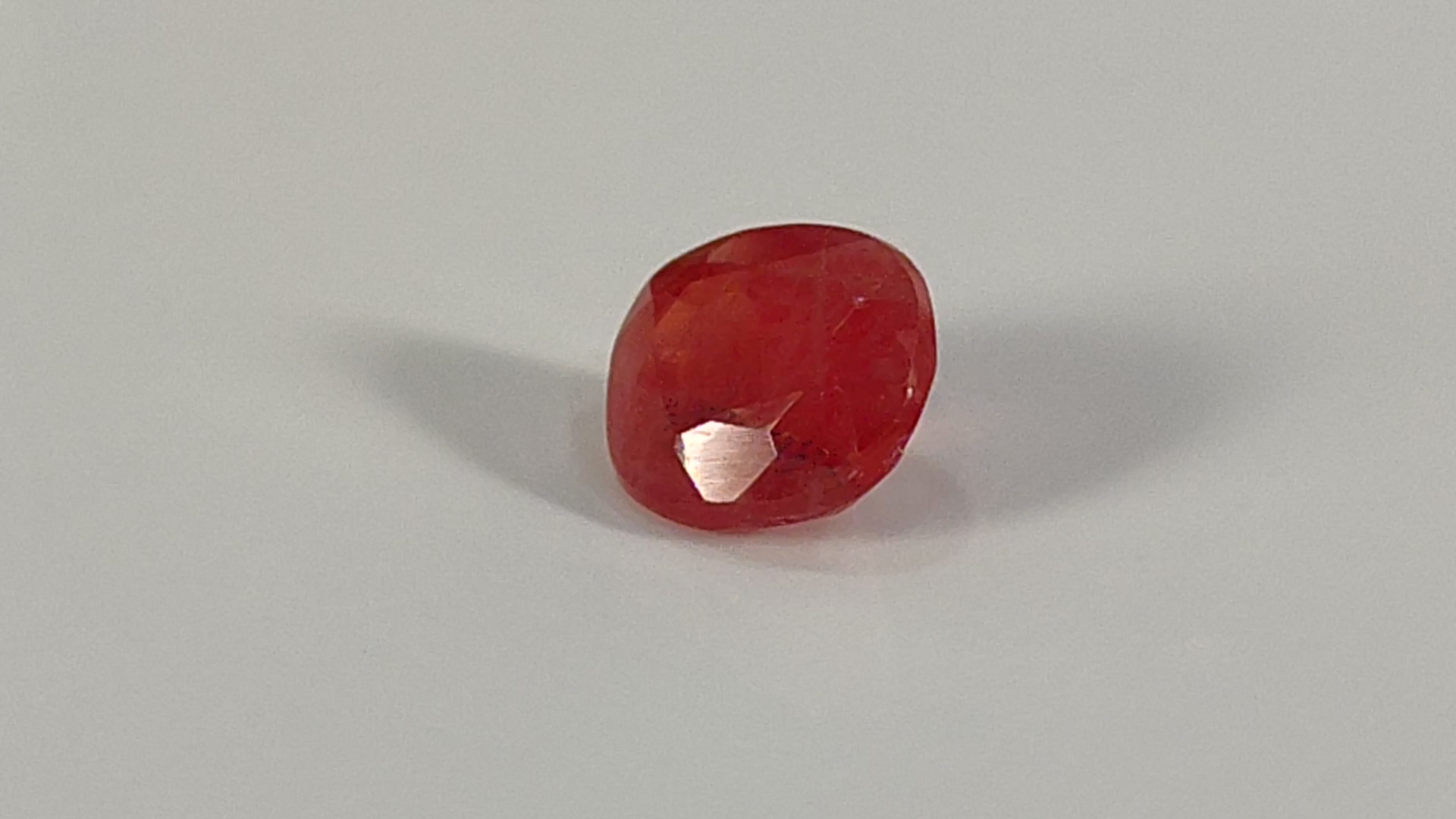 Red gemstone with a faceted cut and a bright reflection.