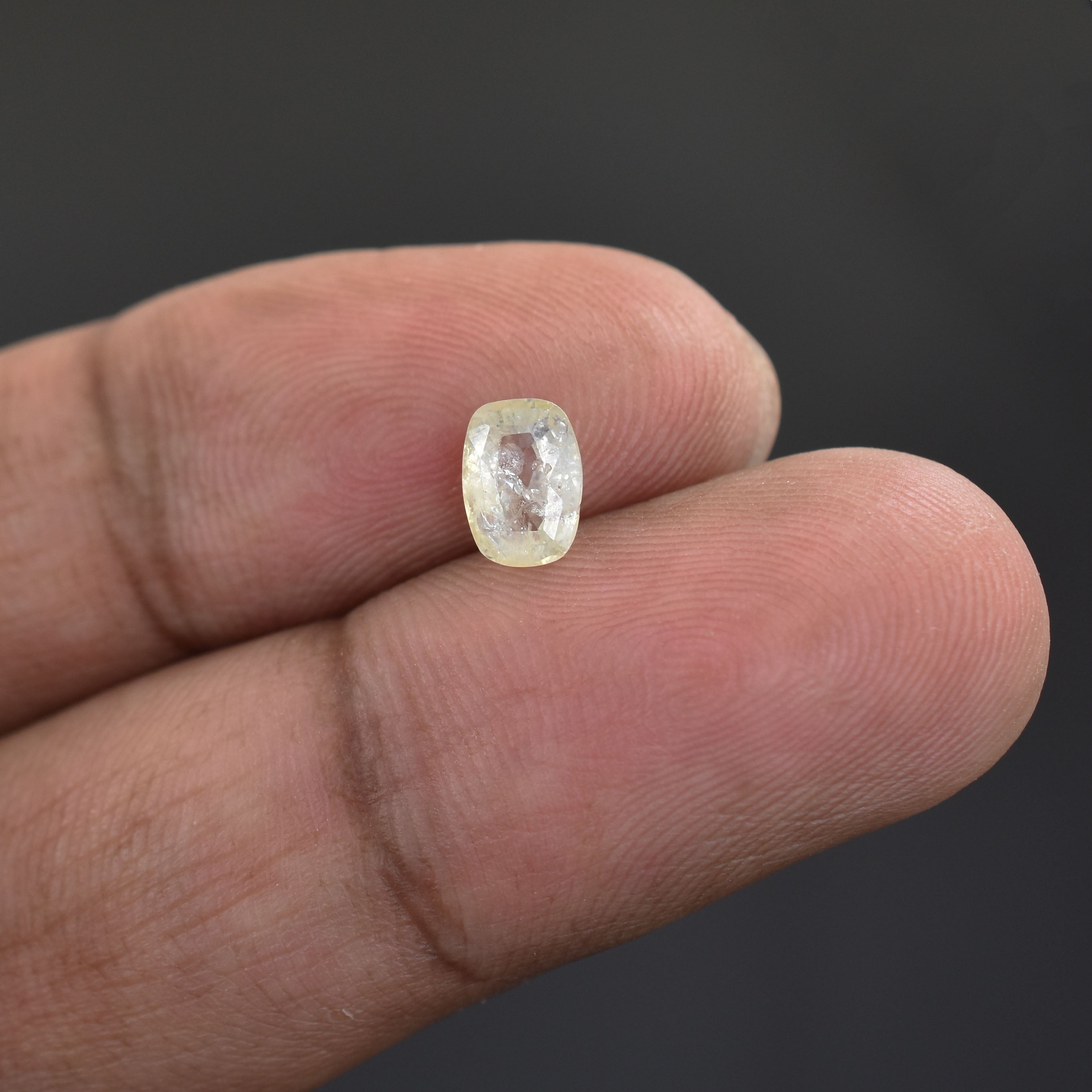 Oval-shaped, translucent gemstone held between two fingers.