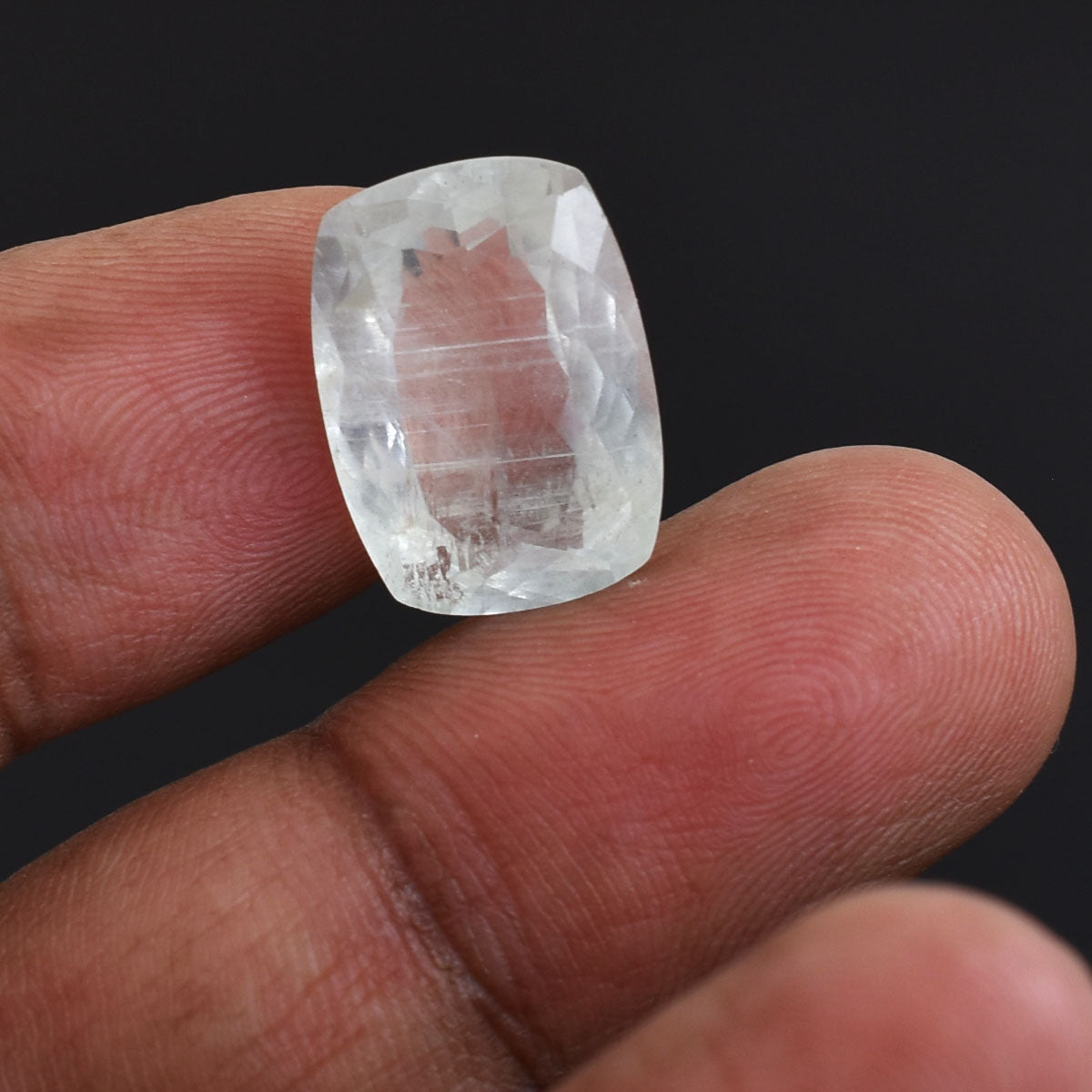 Clear, faceted gemstone or crystal held between two fingers.