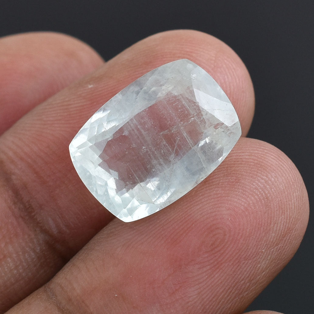 Clear, faceted gemstone held between two fingers.