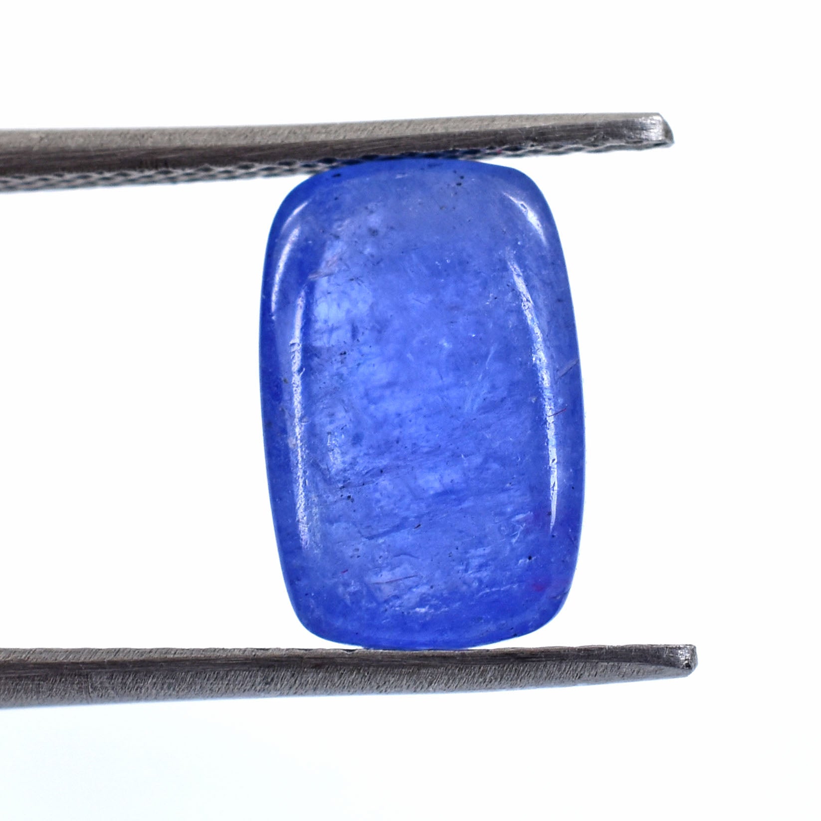 Vibrant blue gemstone with a smooth, cabochon-cut surface held by tweezers.