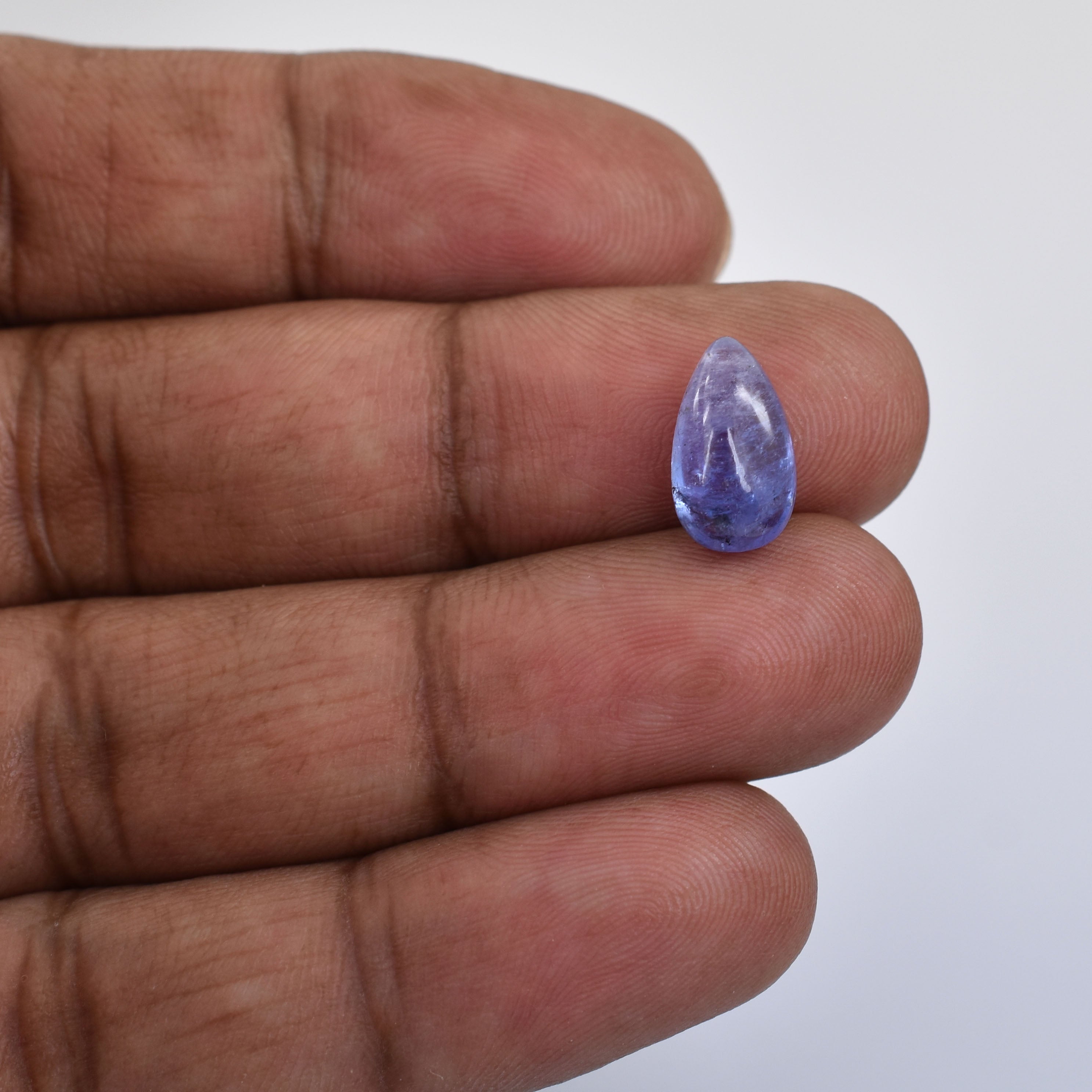 Teardrop-shaped purple gemstone held between fingers.