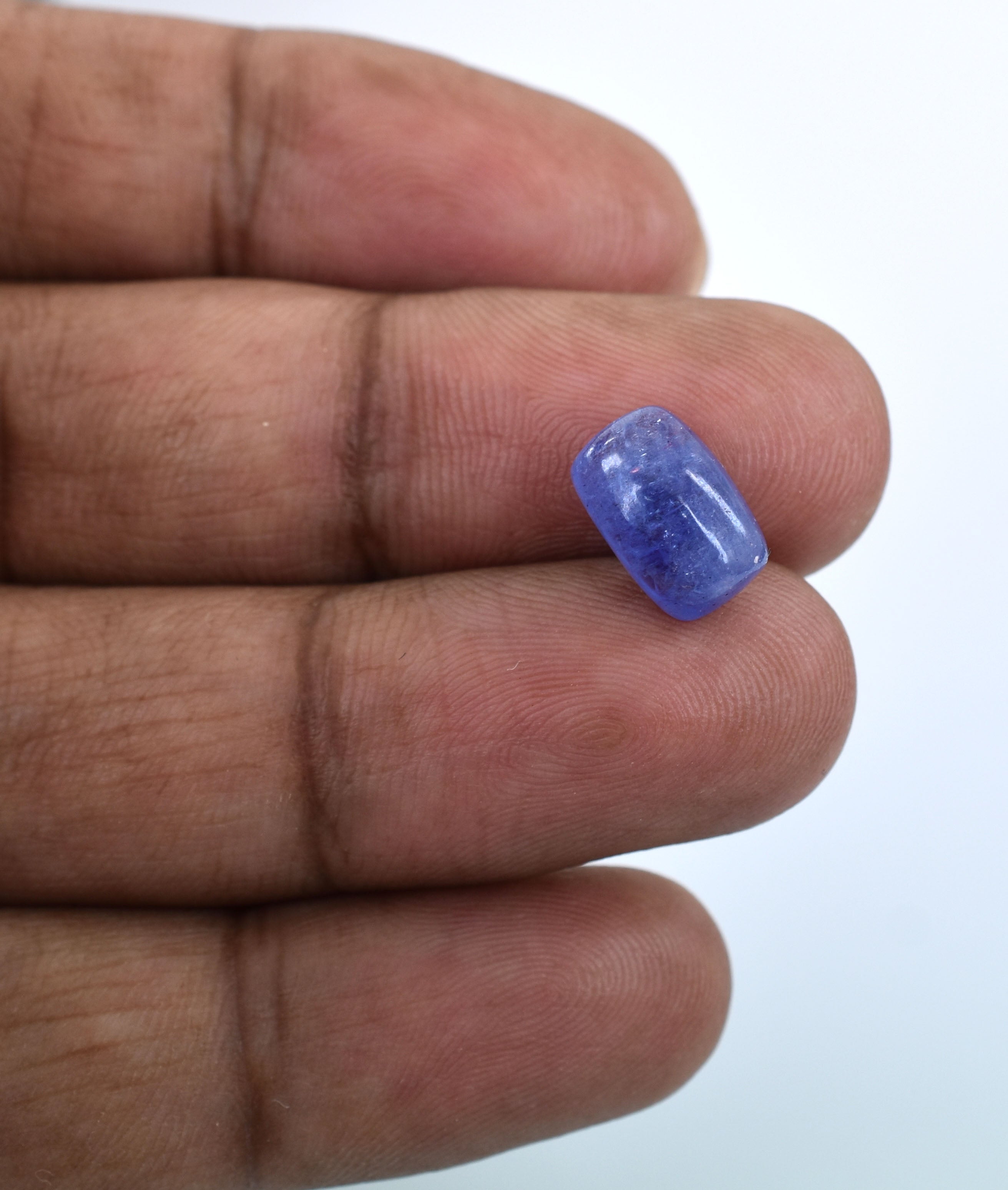 Blue gemstone held between fingertips.